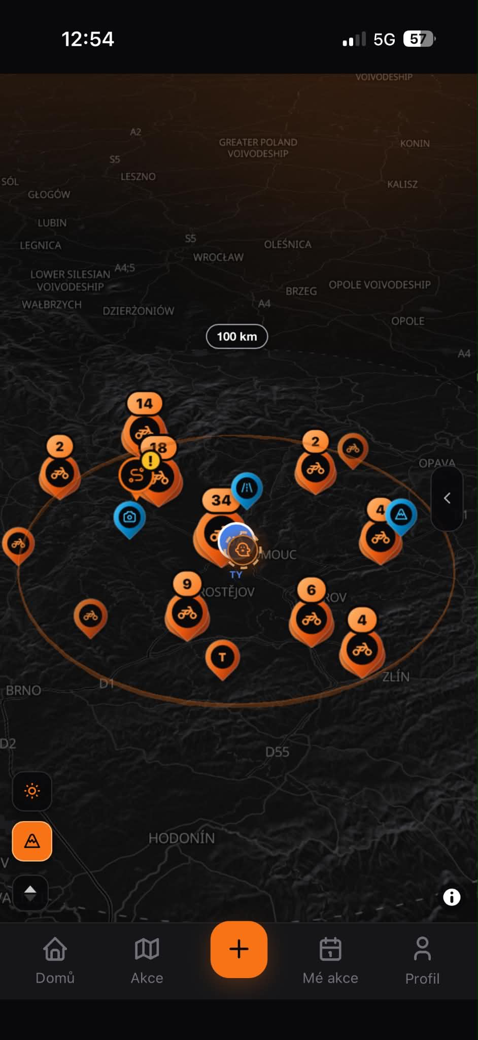 The app's live map with a 100 km search radius drawn around the rider and event pins clustered inside it